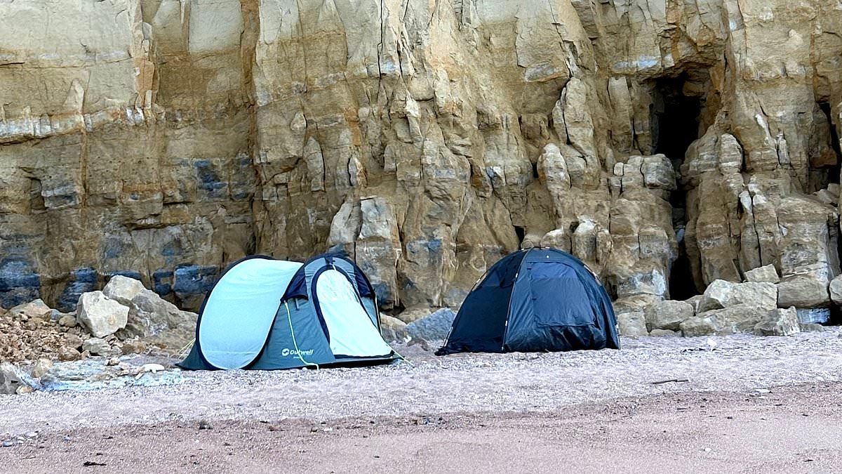 Rocks in their heads! 'Oblivious' campers pitch their tents under dangerous cliff - right next to where rockfall plunged 150ft onto the beach