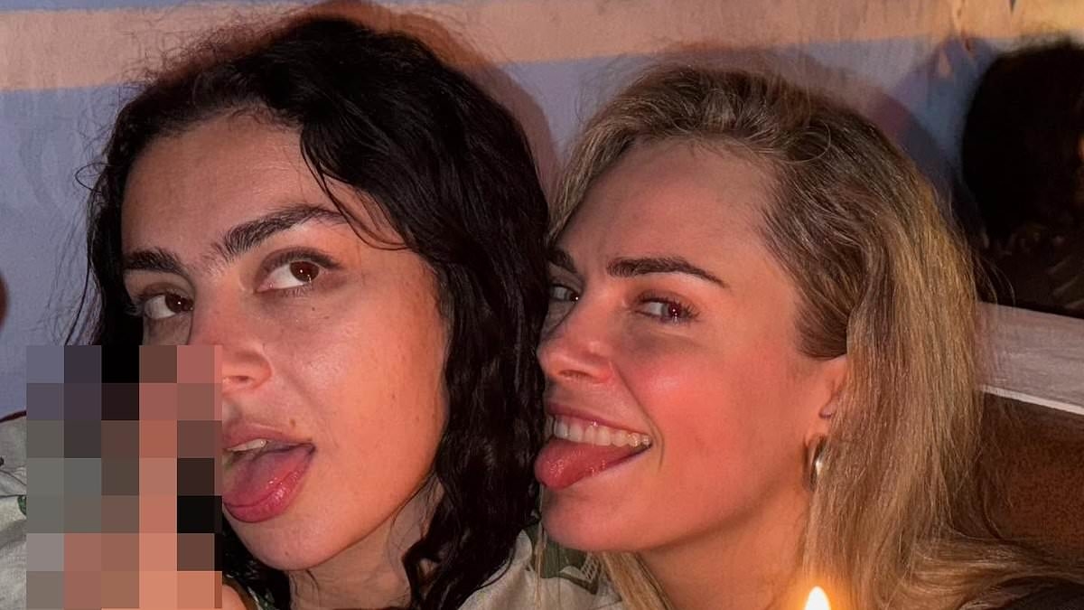 Charli XCX puts on a very leggy display in black hotpants and a crop top as she parties with Cara Delevingne at Glastonbury