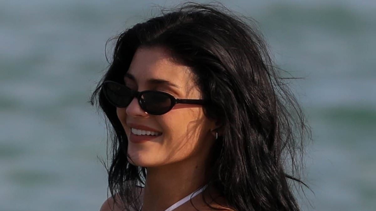 Kylie Jenner flaunts her hourglass curves in a white swimsuit as she joins her bikini-clad sister Kendall frolicking in the ocean at beach club in St Tropez