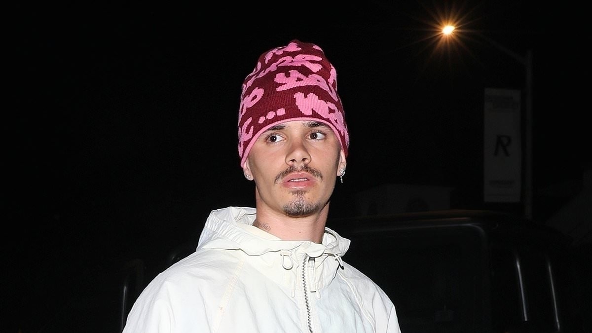 Romeo Beckham hides his new bold pink hair under knitted beanie as he steps out for dinner in Hollywood after shaving his head to channel his father David's famous noughties buzzcut