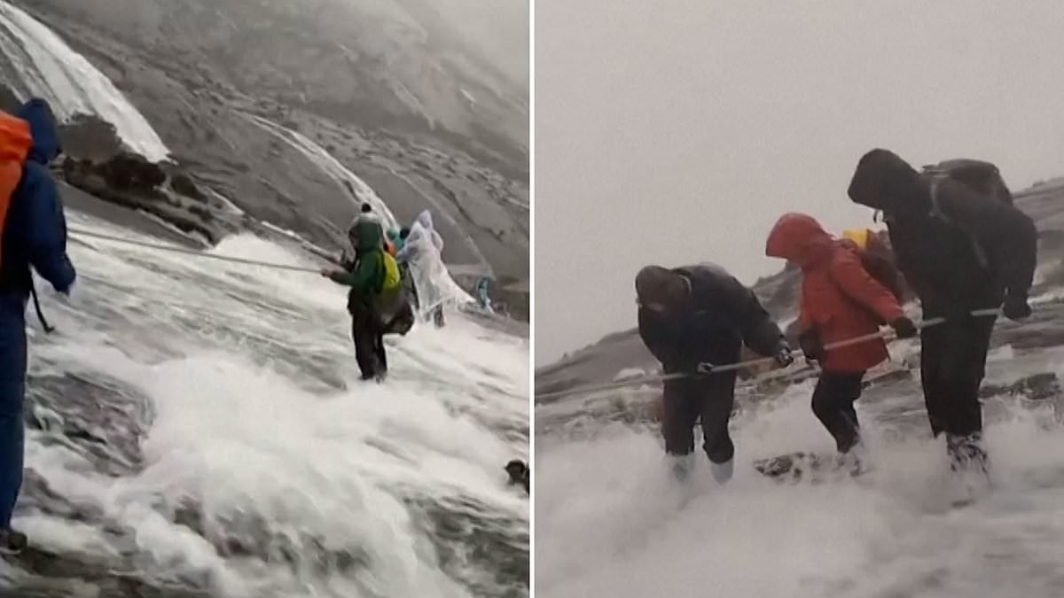 Climbers cling onto a line as they brave fast-flowing water pouring down a mountain in Malaysia