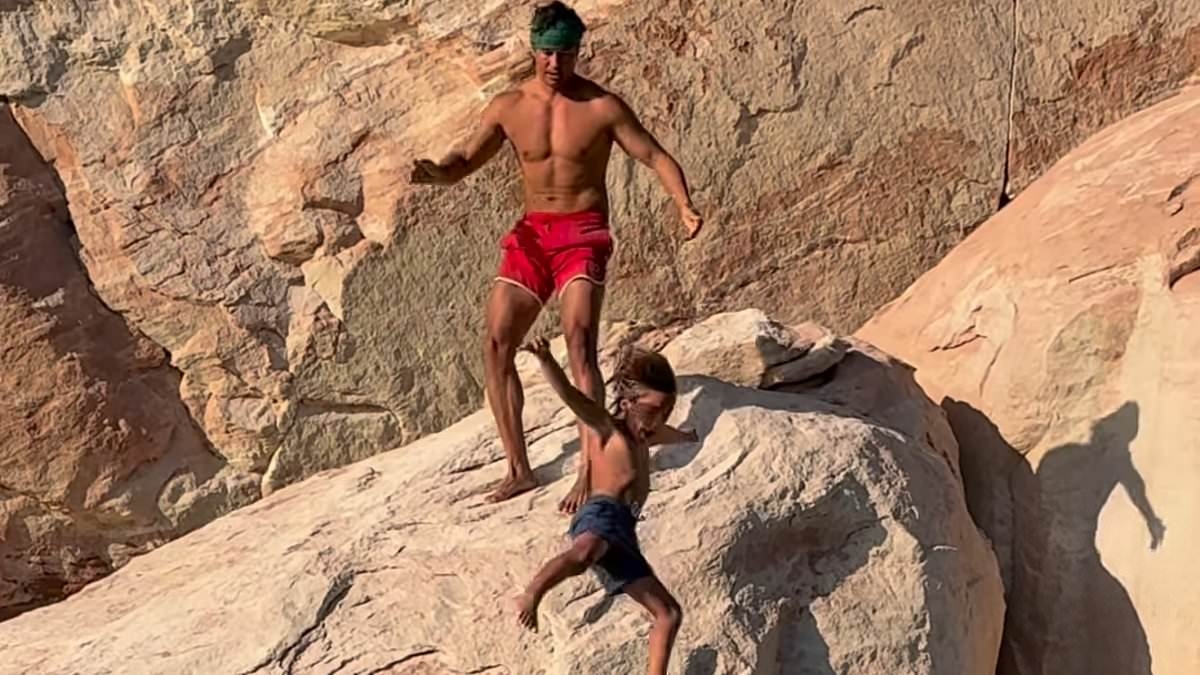Travel influencer sparks fury after tossing son off a cliff in 'wild' parenting moment on lake trip