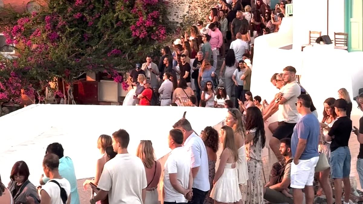 The tourist invasion of 'Instagram island': Thousands of selfie-hunting holidaymakers pack the narrow streets of Santorini to capture sunset view loved by influencers
