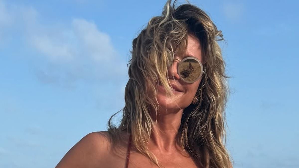 Heidi Klum turns heads in a very skimpy sparkly red bikini displaying her incredible figure as she poses with a kiwi float on the beach