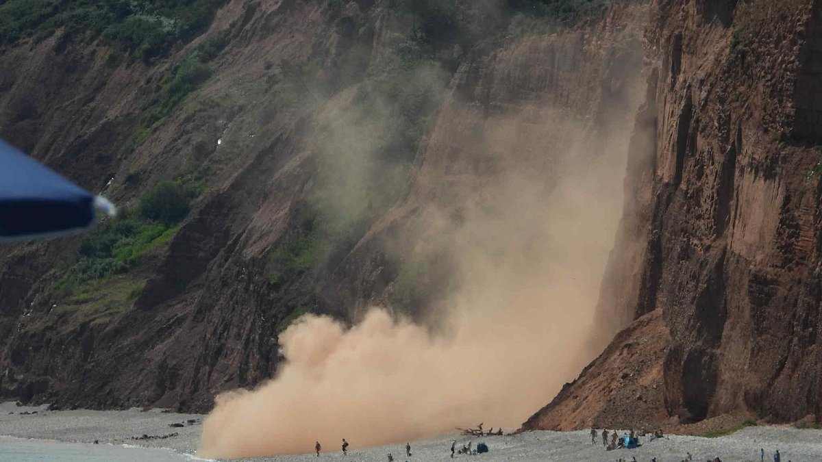 Moment huge rockfall narrowly misses sunbathers as 'thousands of tons' of cliff stone crashes down onto beach