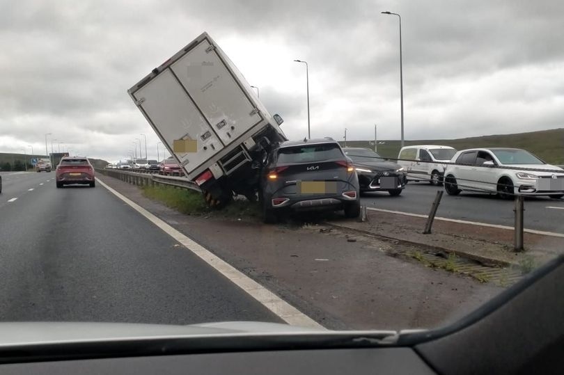 Horror moment lorry smashes into central reservation with car wedged UNDERNEATH on M62